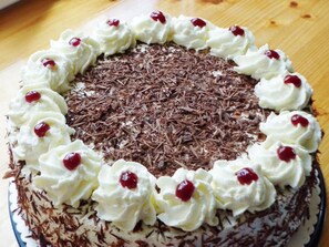 A round cake with whipped cream and cherries on top, surrounded by chocolate shavings. - Pleasant Holiday Home With Balcony (Sankt Peter)