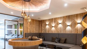 A modern lounge area with a wooden wall, a round wooden table, and a grey sofa. - Modern Holiday Apartment With Balcony (Fuegen)