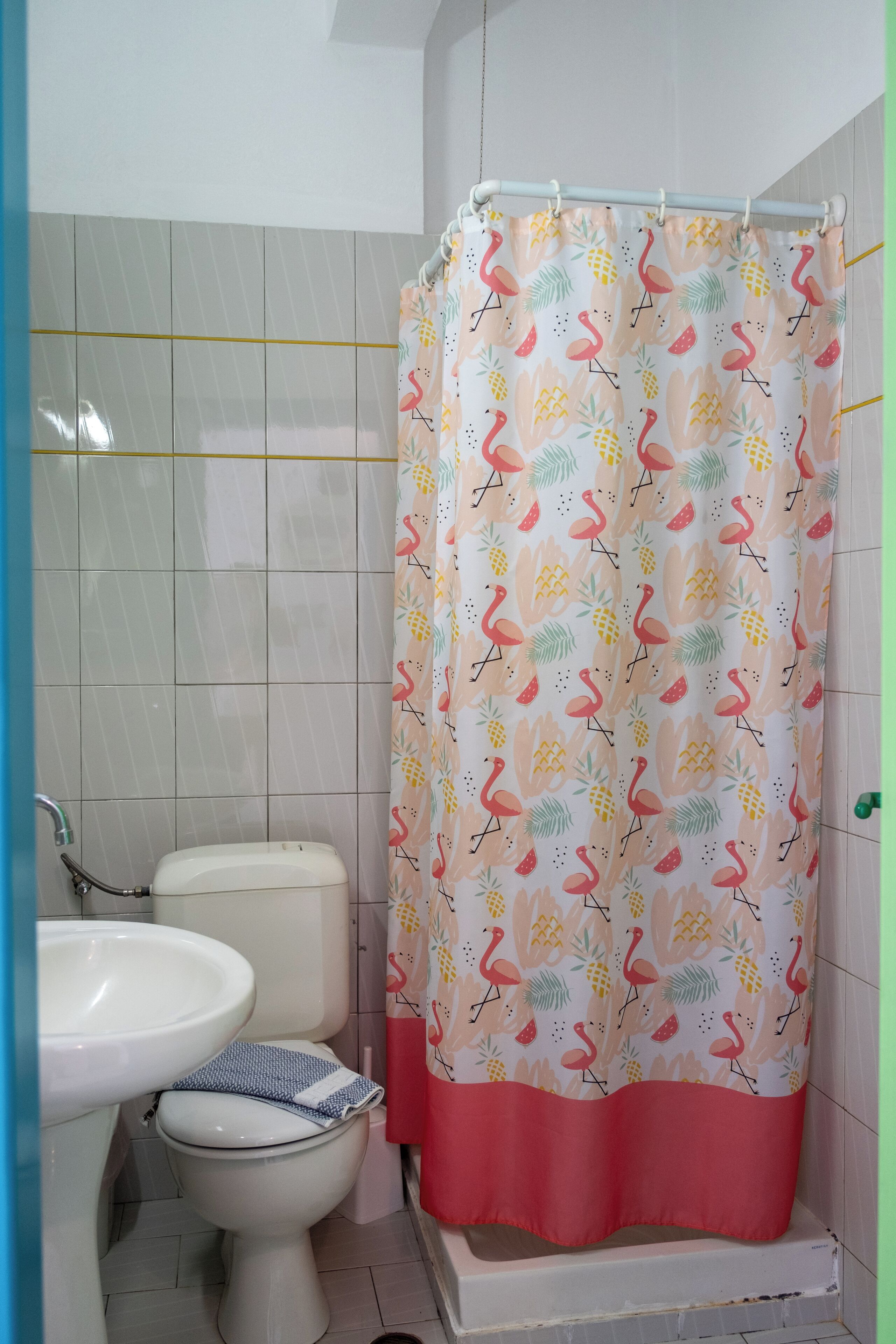 Un baño con inodoro, lavabo y cortina de ducha con estampado tropical.