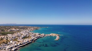 Vue aérienne d’une ville côtière avec un port de plaisance, des bâtiments le long du front de mer et des eaux d’un bleu limpide.