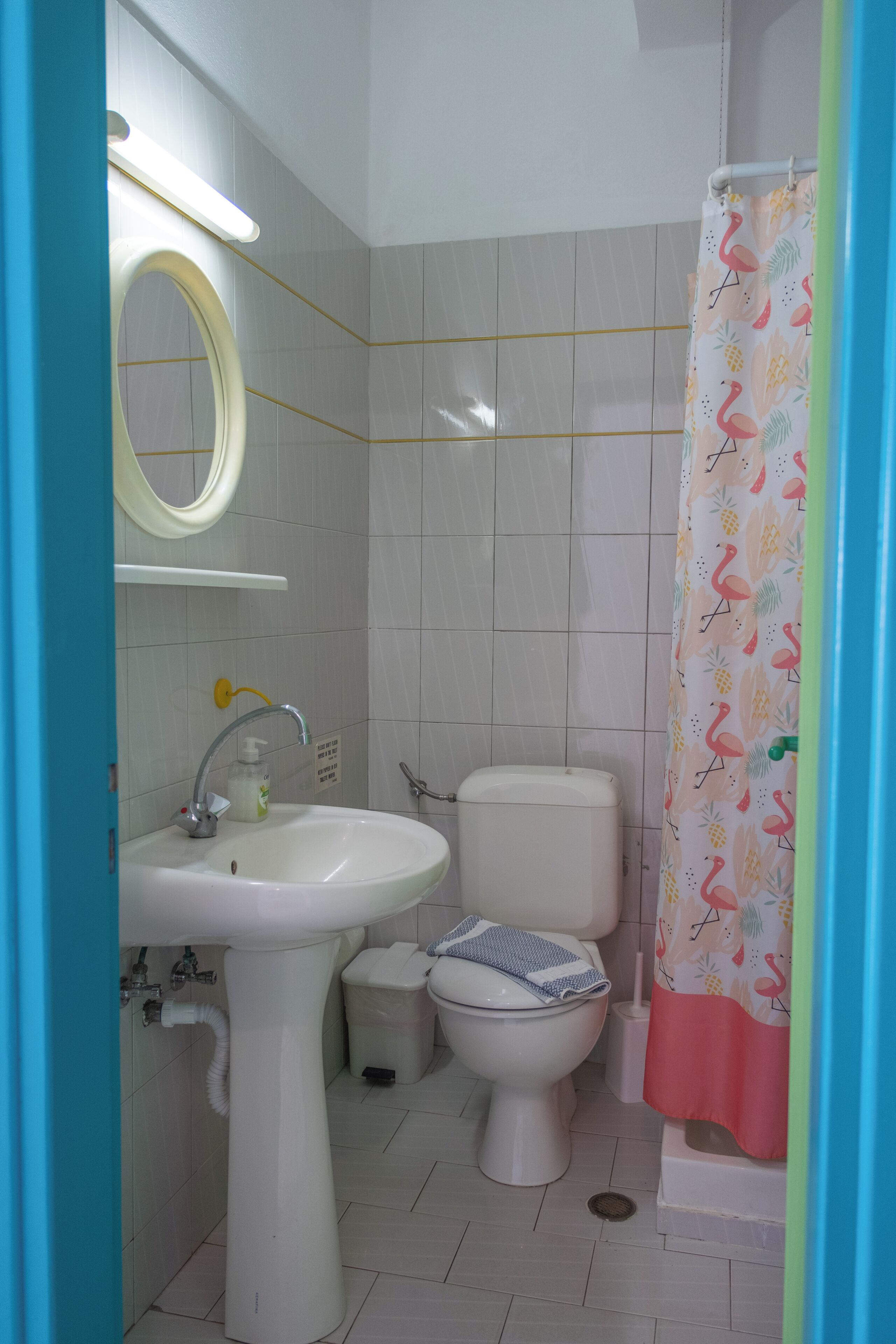 Un baño con lavamanos, espejo, inodoro y cortina de ducha.