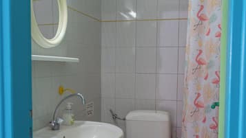 Un baño con lavamanos, espejo, inodoro y cortina de ducha.