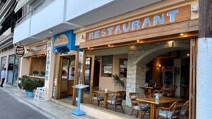 A restaurant with outdoor seating, a signboard, and a small outdoor table with chairs. - Enplo Apartments (Hersonissos)