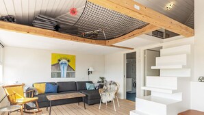 A modern living room with a wooden ceiling, a sofa, a rocking chair, and a staircase. - Family Holiday Home in Karrebaeksminde (Karrebæksminde)