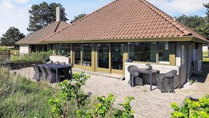 A house with a tiled roof, large glass windows, and outdoor seating. - Family Holiday Home in Karrebaeksminde (Karrebæksminde)