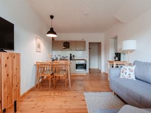 Cozy living space with a dining area, kitchenette, and seating area featuring a sofa and flat-screen TV.