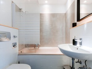 Ein modernes Badezimmer mit Badewanne, Waschbecken und Toilette.