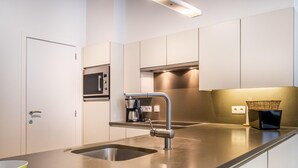 A modern kitchen with stainless steel appliances, a built-in microwave, and a coffee maker. - Apartment in St-idesbald Near the Beach (Koksijde)