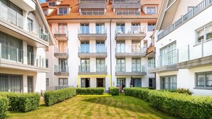 A modern multi-story residential building with balconies, large windows, and a central courtyard with a lawn and hedges. - Apartment in St-idesbald Near the Beach (Koksijde)