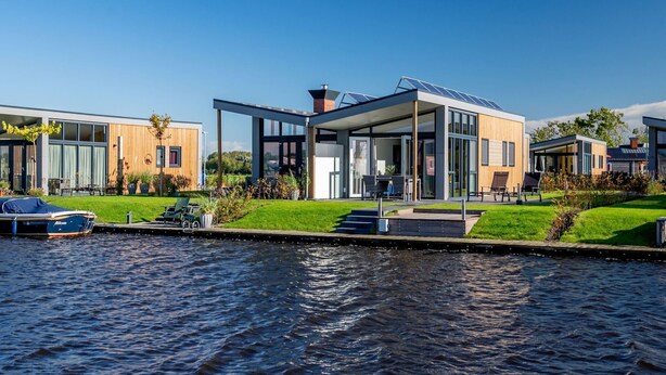 Une propriété moderne située au bord de l’eau, dotée d’un patio entièrement vitré, d’un quai pour bateaux et offrant une vue sur le canal.