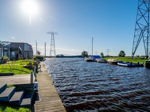 Une vue sur la rivière, avec un quai en bois, des bateaux et un bâtiment moderne.