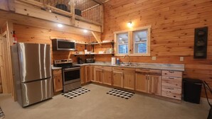 Eine Küche mit Holzwänden, einem Edelstahlkühlschrank, einer Mikrowelle, einem Backofen und einem Spülbecken.