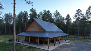 Eine rustikale Holzhütte mit Metalldach, umgeben von einer Veranda und einem Schotterweg.