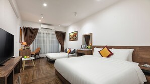 Une chambre d’hôtel avec deux lits, une télévision, un bureau avec une lampe et une chaise.