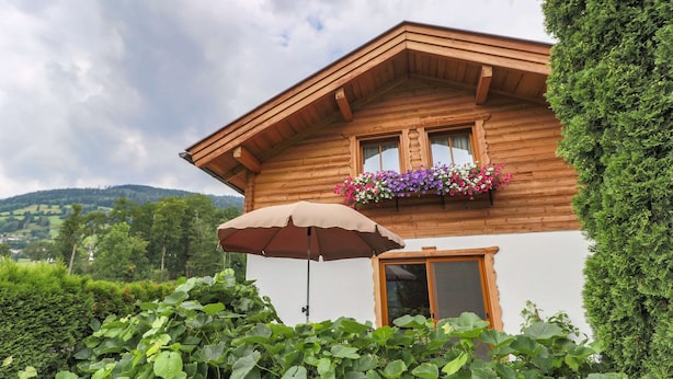 A wooden house with a balcony, surrounded by lush greenery. - Cosy Holiday Home Near ski Area (Piesendorf)