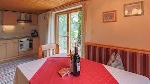 A cozy kitchen with wooden cabinets, a stove, and a dining area with a table set for two. - Cosy Holiday Home Near ski Area (Piesendorf)