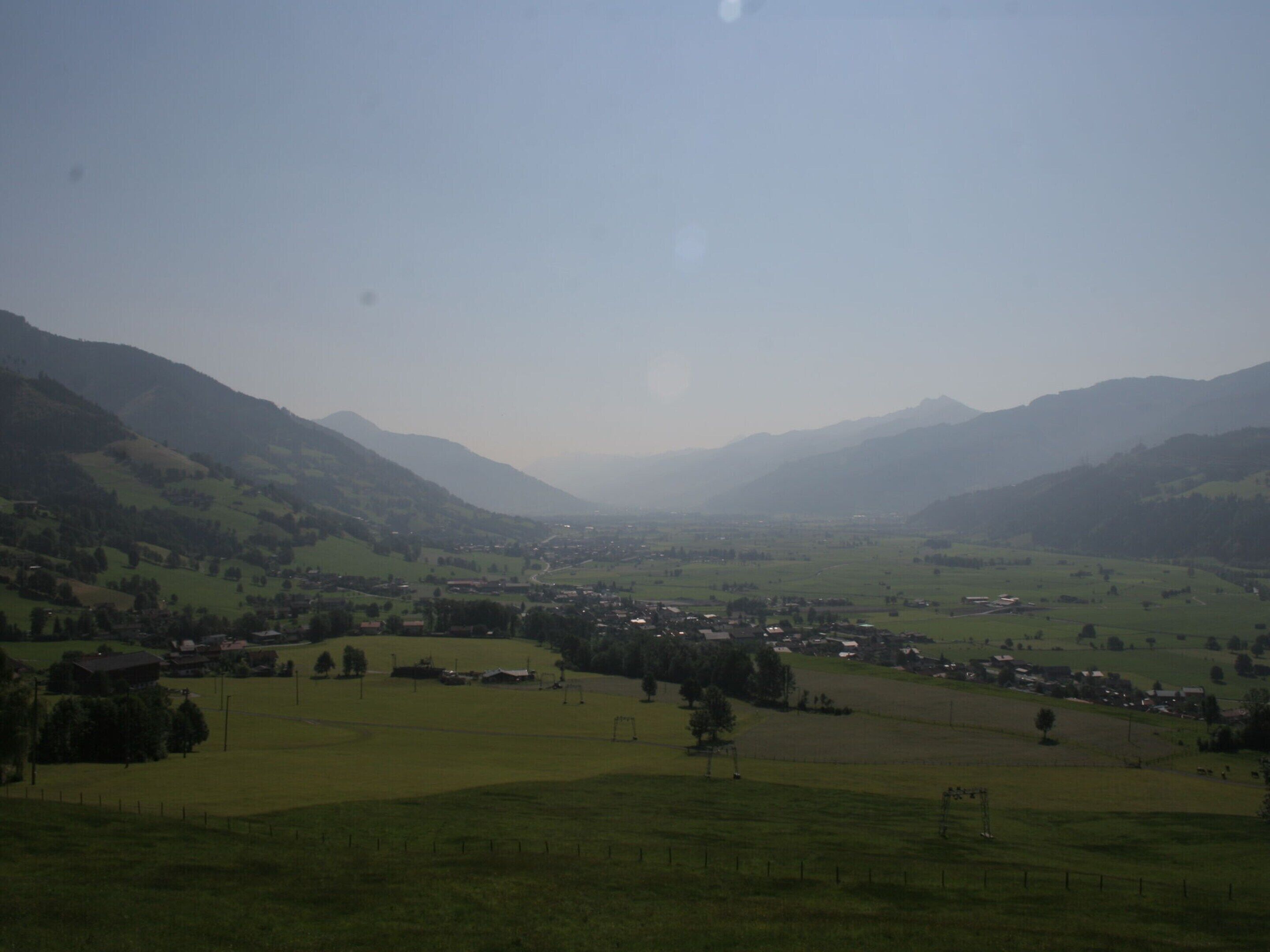 Un paisaje rural con colinas ondulantes, un pequeño pueblo y un cielo despejado.