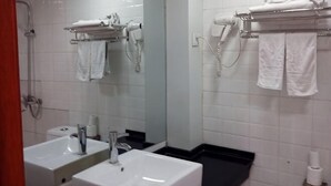 Een badkamer met twee wasbakken, een spiegel, een handdoekhouder en een douche.