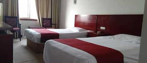 A hotel room with two beds, a desk, and a chair.