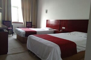 A hotel room with two beds, a desk, and a chair.