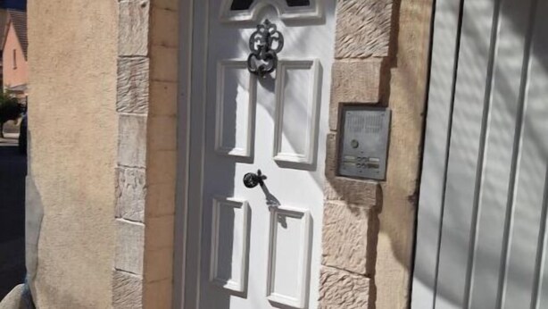 A white door with a number plate '3' and a small plaque, set in a stone wall with a simple, clean design.
