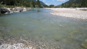 A clear river with rocky banks and forested hills in the background. - Plaatsje in het Mesnerhuis (Lenggries)