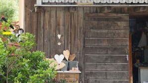 A rustic wooden building with a balcony, a window, and a door. - Plaatsje in het Mesnerhuis (Lenggries)