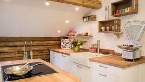 A kitchen with wooden beams, white cabinets, a wooden countertop, a stove, and a scale. - Plaatsje in het Mesnerhuis (Lenggries)