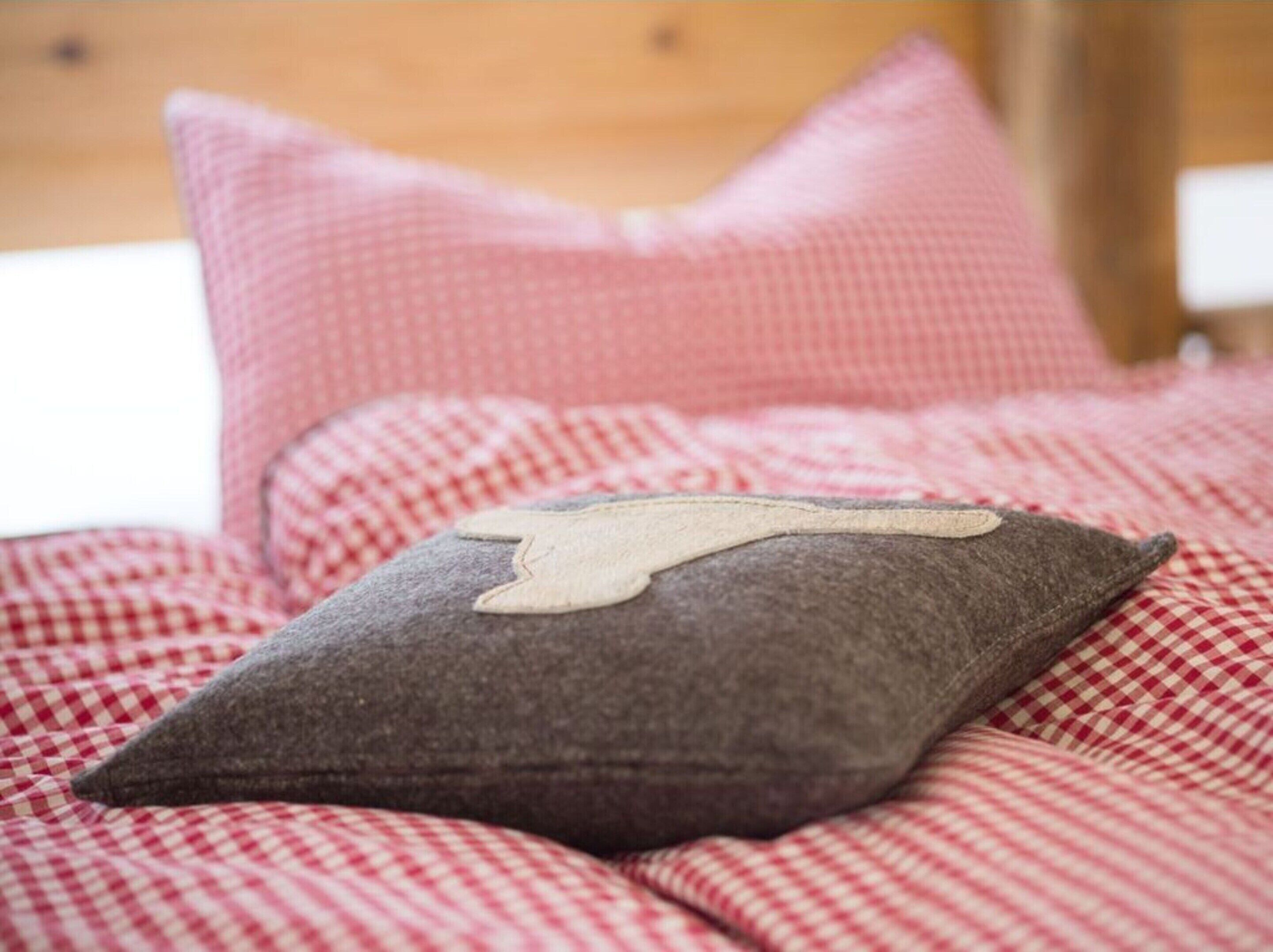 Un lit avec une couvre-lit à carreaux et un oreiller orné d’un motif.