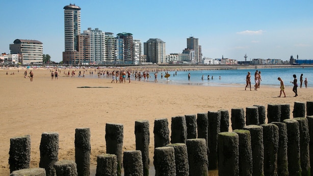 A beach with a city skyline in the background, wooden posts in the foreground, and people enjoying the beach. - Apartment in Vlissingen Near the Beach (Vlissingen)