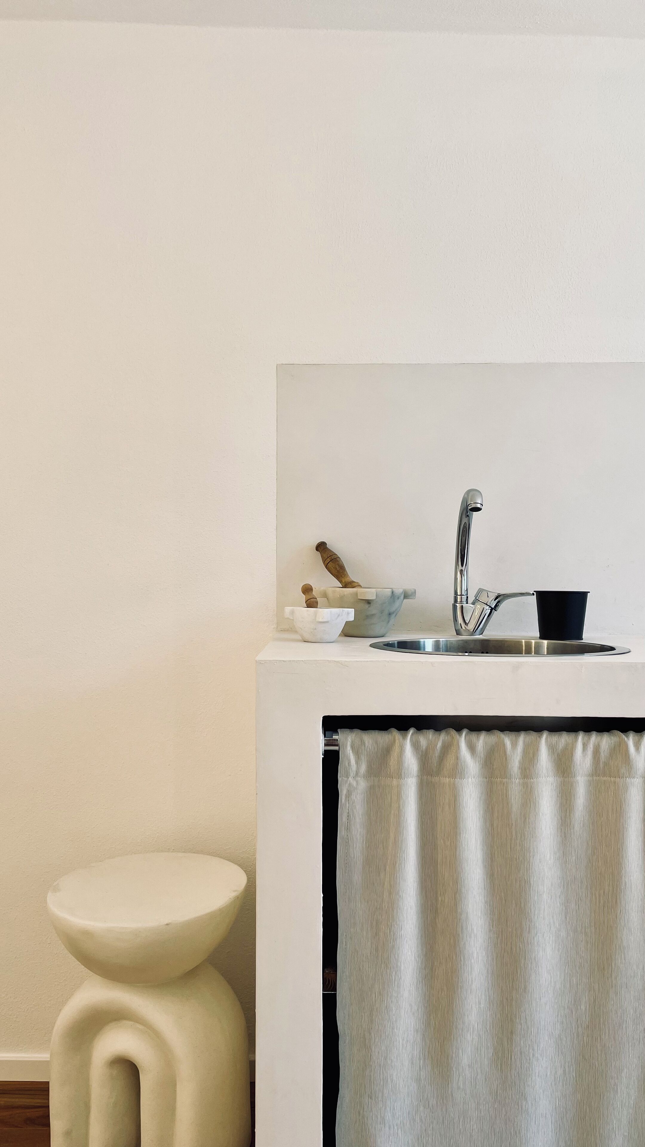 Un baño con un lavabo blanco, una taza negra, una encimera de mármol y un inodoro blanco.