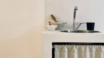 Un baño con un lavabo blanco, una taza negra, una encimera de mármol y un inodoro blanco.