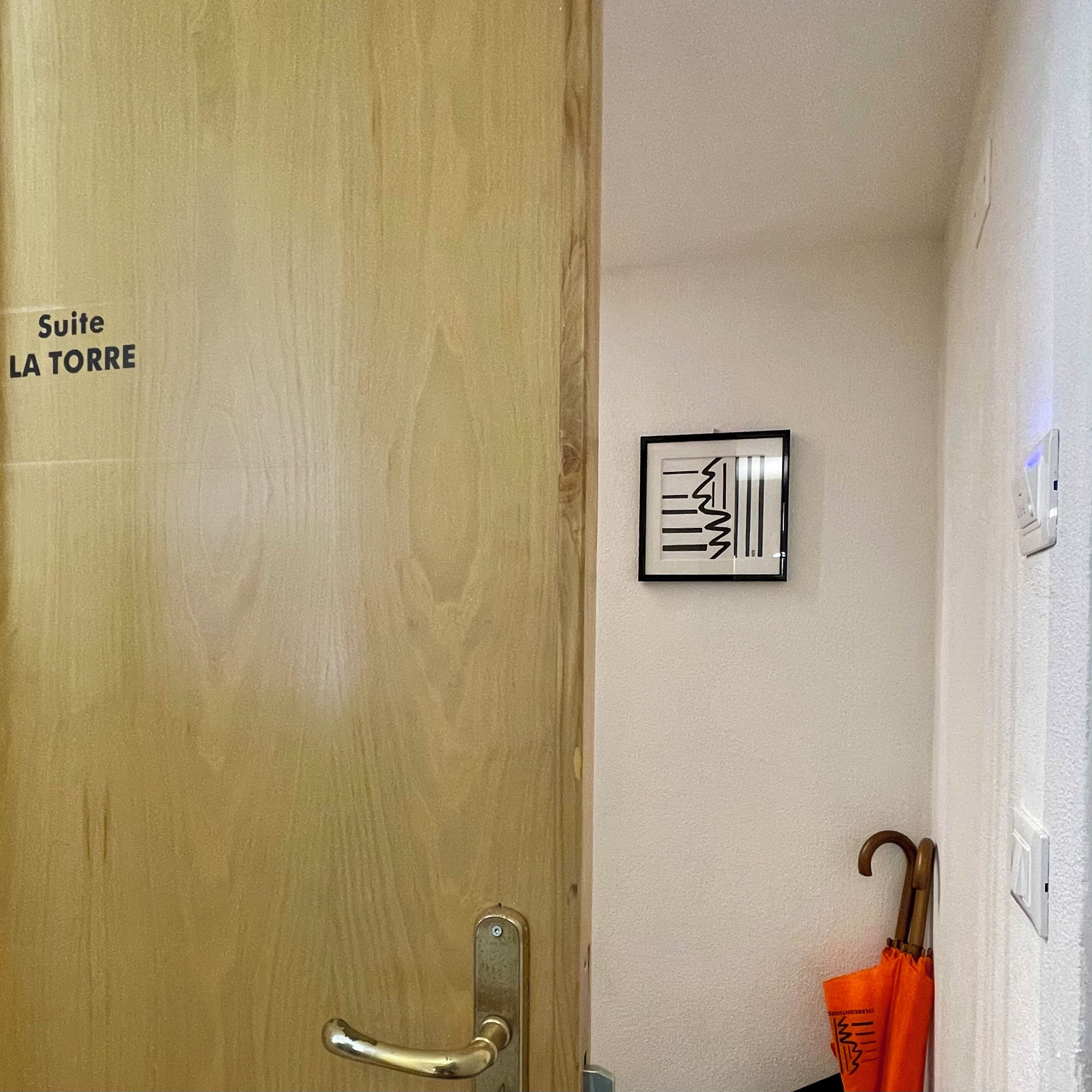 A wooden door with a handle and a sign reading "Suite LA TORRE".