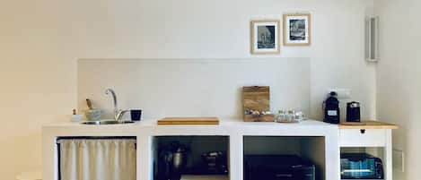 A compact kitchen with a sink, a coffee maker, and a refrigerator.