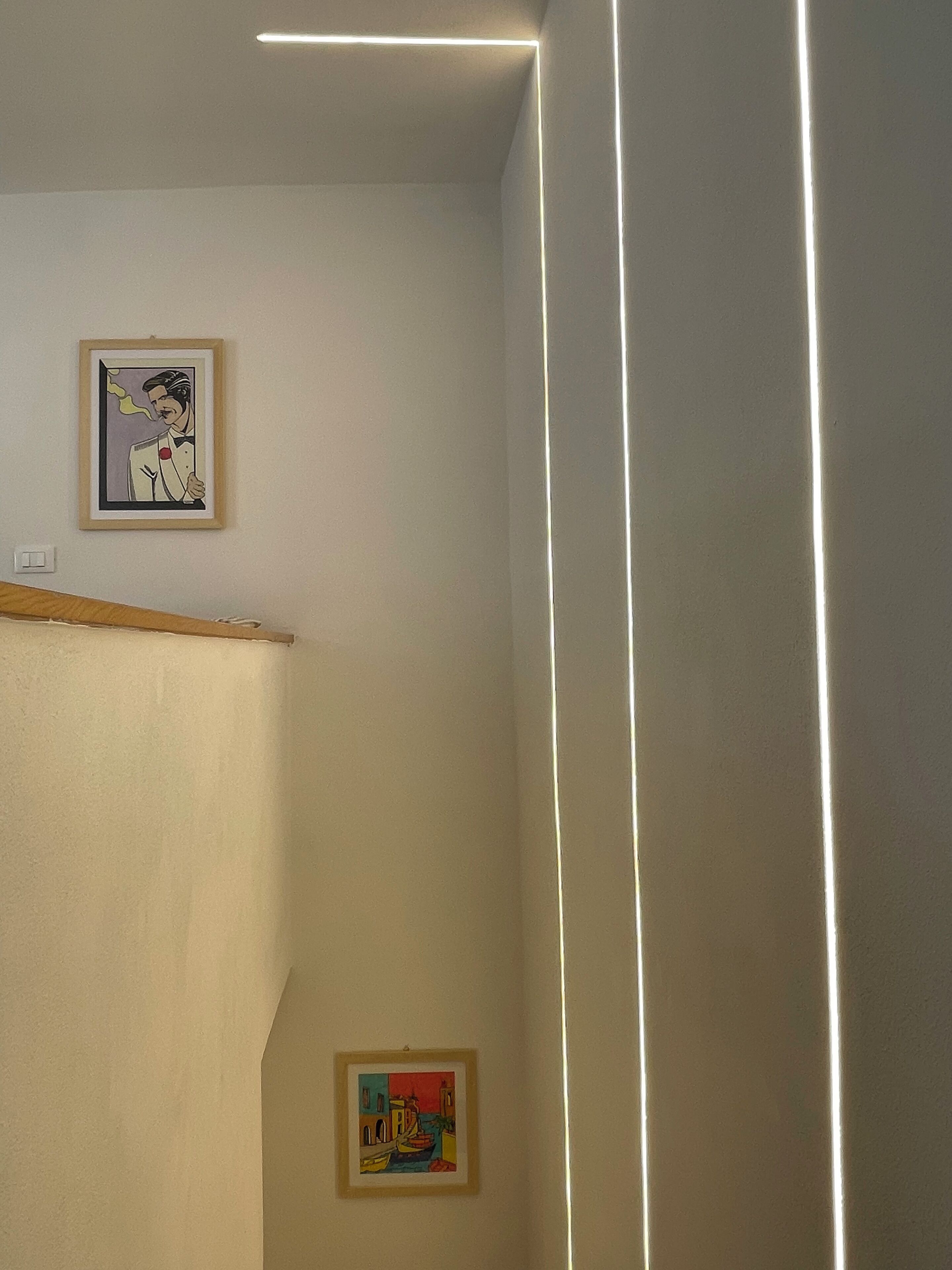 Une pièce avec un plafond en pente et deux œuvres d’art encadrées accrochées au mur.