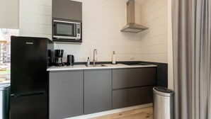 Une cuisine moderne avec un réfrigérateur noir, un four à micro-ondes encastré, un évier en acier inoxydable et une cuisinière à gaz.