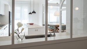 Moderni keittiö, jossa on keskeinen saareke, riippuvalaisimet sekä ruokailutila pyöreän pöydän ja tuolien ympärillä.