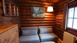 A cozy log cabin room with a sofa and a small wooden table. - Wastl Comfortable Holiday Residence (Woergl)