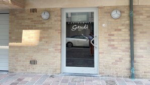 A building entrance with a glass door, a brick wall, and a car parked outside. - Apartment in Nieuwpoort by the Beach (Nieuwpoort)