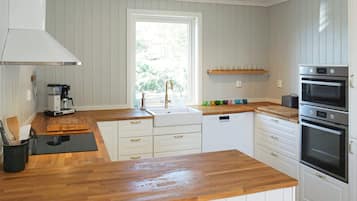 Eine Küche mit weißen Schränken, einer Holz Arbeitsplatte, einer Kaffeemaschine, einem Spülbecken und einem eingebauten Backofen.
