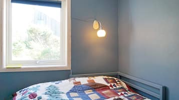 Une chambre à coucher avec un lit, une fenêtre et un luminaire fixé au mur.