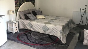 A bedroom with a bed, a nightstand, a lamp, a rug, and a framed picture on the wall.
