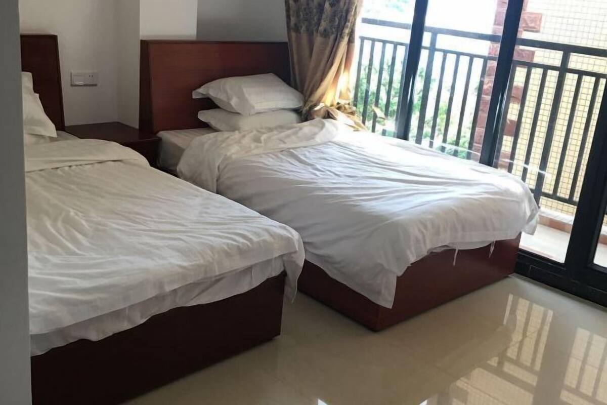 A hotel room with two beds, a wooden headboard, and a view of the outside balcony.