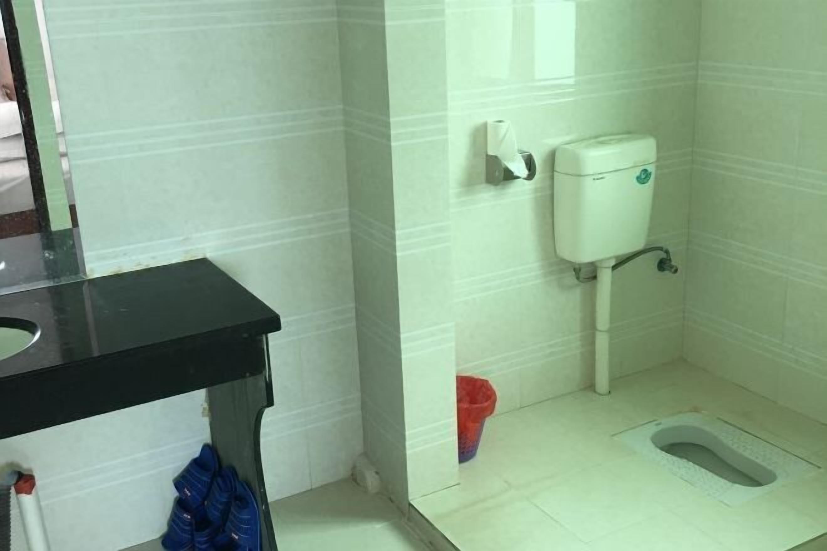Un baño con inodoro, lavamanos y cubo de basura.