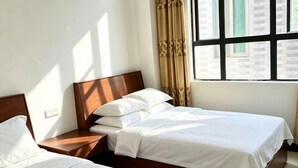 A hotel room with two single beds, a wooden headboard, a nightstand, and a window with curtains. - Tinghai Yushu Hotel (Taishan)