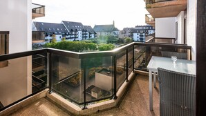 A balcony with a glass railing, a table, and a chair. - Apartment in Koksijde Near the Sea (Koksijde)