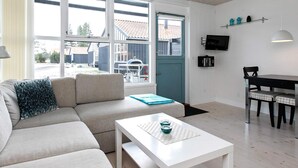 Un salon moderne avec un canapé d’angle, une table basse blanche et un coin repas comprenant une table et des chaises.