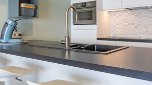 A modern kitchen with a stainless steel sink, a built-in oven, and a coffee machine. - Apartment on the 5th Floor With sea View (Middelkerke)
