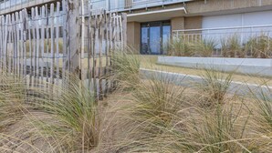 A multi-story building with a balcony, a wooden fence, and dry grass in the foreground. - Apartment on the 5th Floor With sea View (Middelkerke)