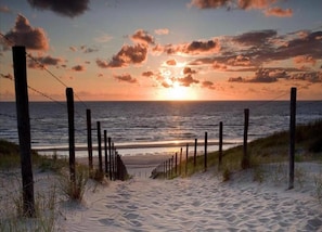 A beach with a wooden fence leading to the ocean, under a sunset sky. - Holiday Home Noordwijkerhout by Beach (Noordwijkerhout)